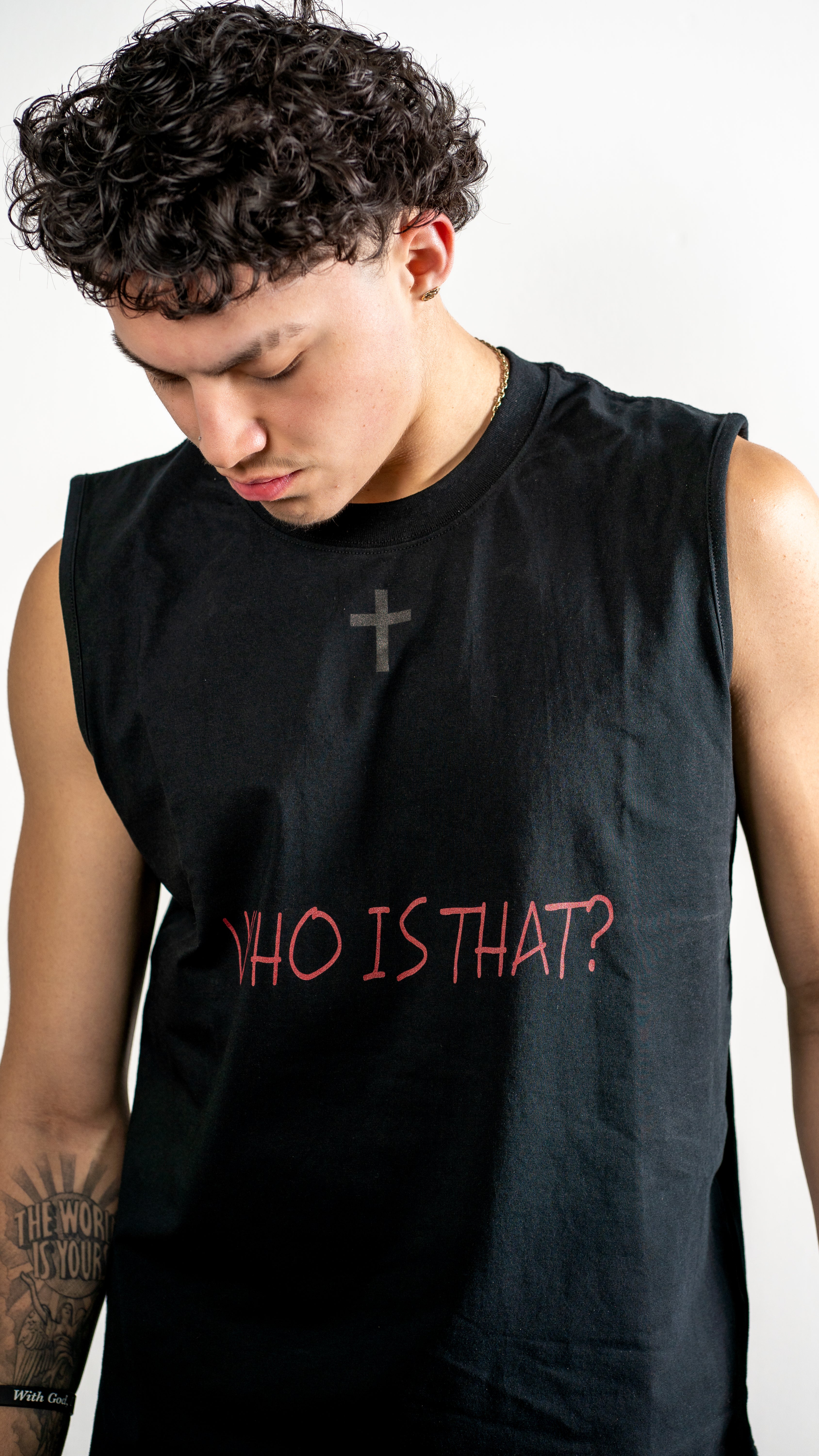 Person wearing a black sleeveless shirt with 'WHO IS THAT?' text on a plain background
